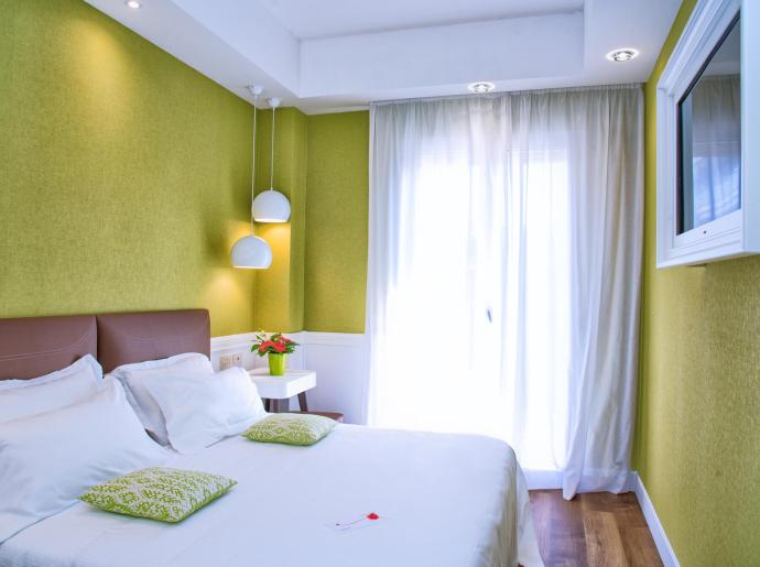 Modernes Zimmer mit grünen Wänden und Doppelbett.
