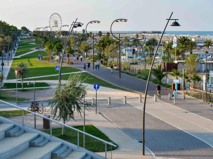 Passeggiata sul lungomare con pista ciclabile, spiaggia e ruota panoramica.