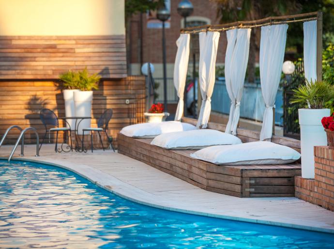 Pool mit Liegen, weißen Vorhängen und dekorativen Pflanzen.