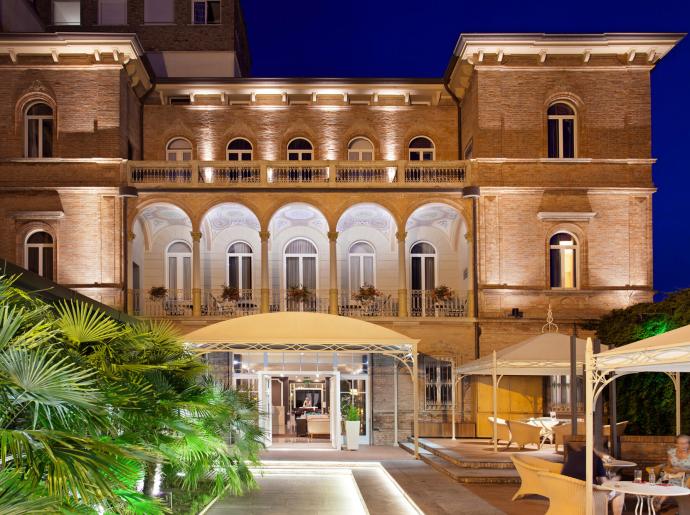Edificio storico illuminato di notte con archi e terrazza.