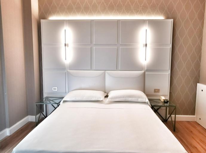 Camera da letto moderna con letto matrimoniale e illuminazione soffusa.