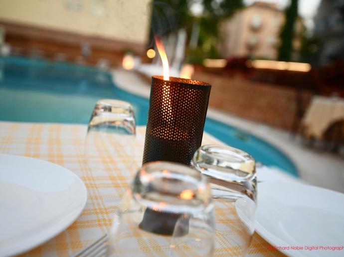 Gedeckter Tisch mit brennender Kerze am Pool.