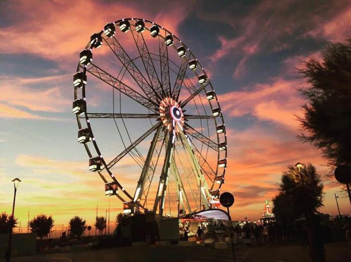 Ruota panoramica al tramonto con cielo colorato.