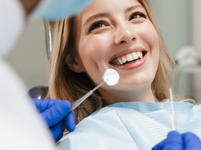 Femme souriante chez le dentiste pendant un contrôle.