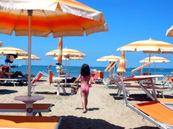 Spiaggia con ombrelloni arancioni e persone che si rilassano.