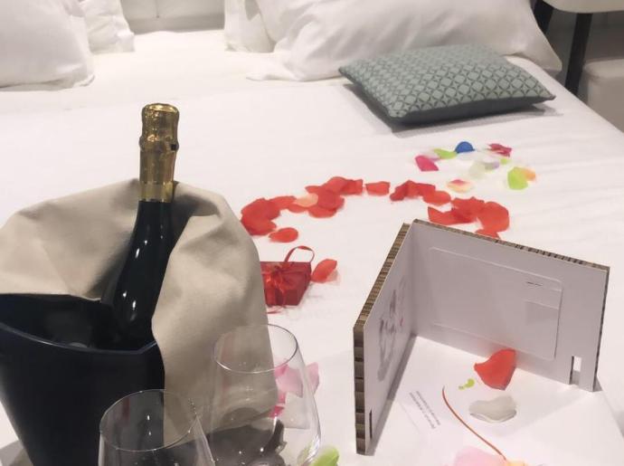 Camera romantica con petali di rosa, champagne e calici.