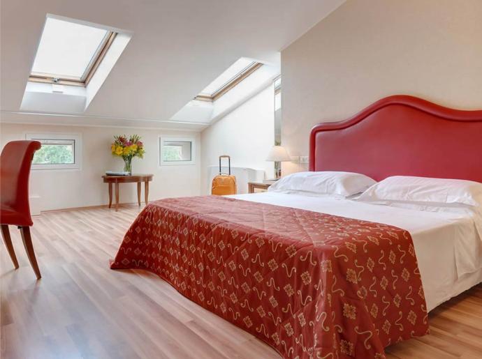 Helles Schlafzimmer mit Dachfenstern und Doppelbett.