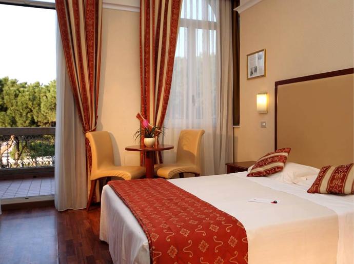Camera d'albergo elegante con vista sul verde e arredi raffinati.