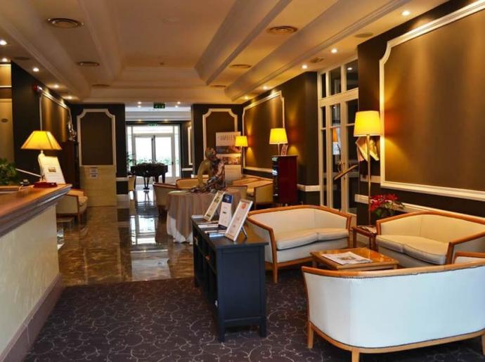 Elegante hall con divani, lampade e reception in un hotel.