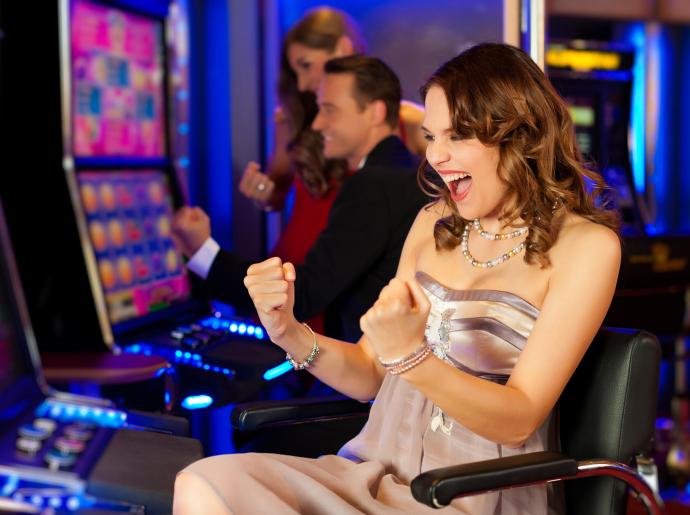 Persone felici giocano alle slot machine in un casinò.