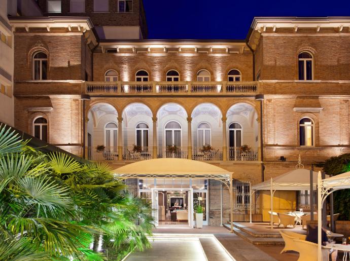 Elegante edificio storico con archi e terrazza, illuminato di notte.