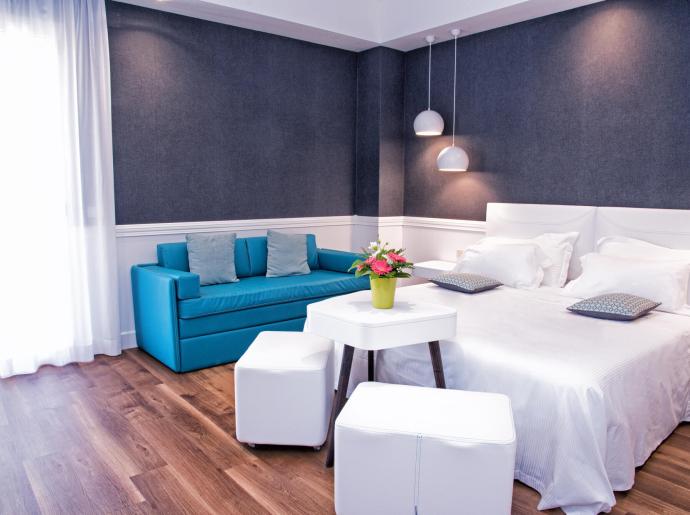 Camera moderna con letto, divano blu e decorazioni eleganti.